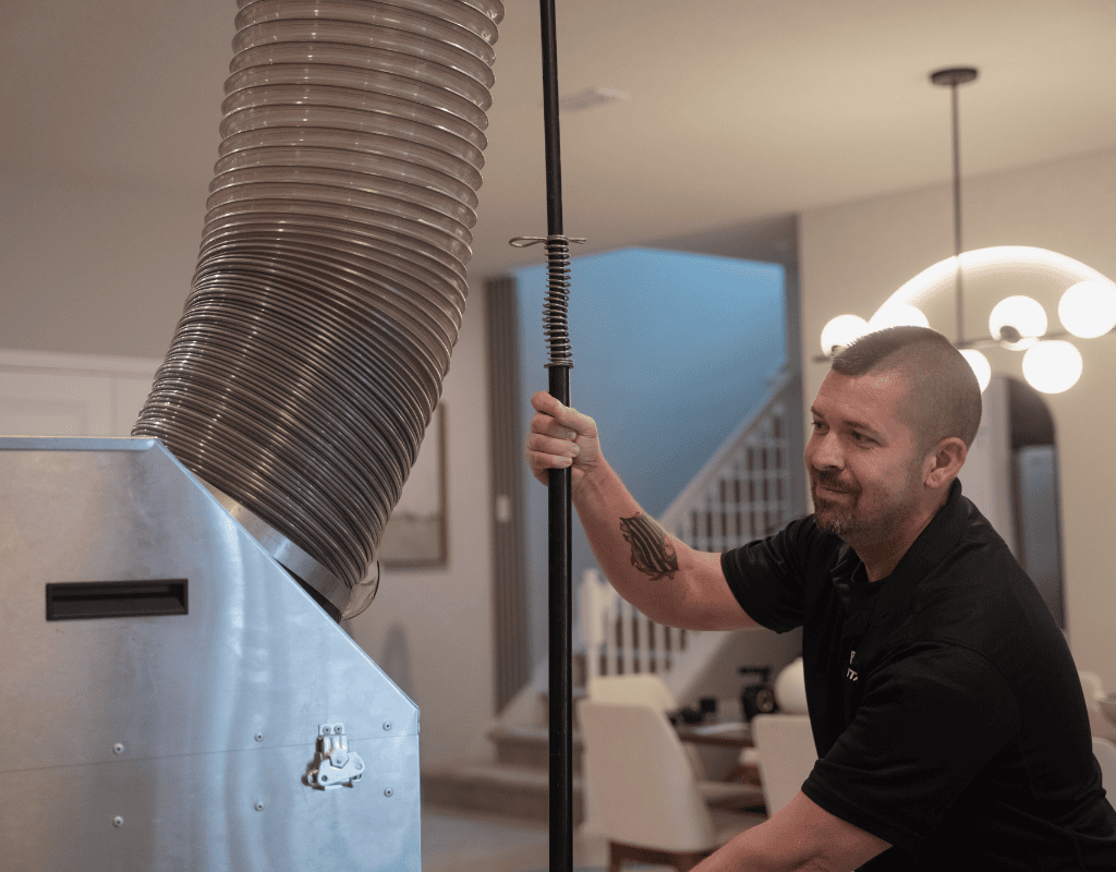 Air Titans expert using high-powered vacuum hose to clean air ducts inside a Tampa home