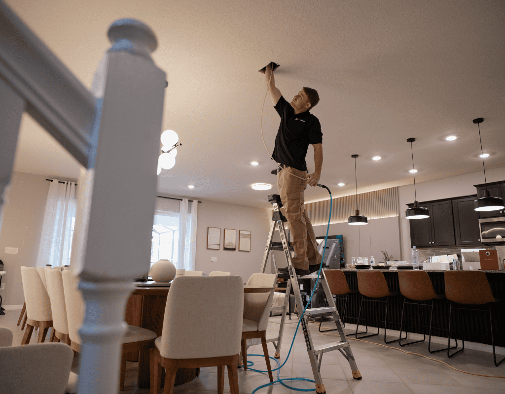 Air Titans specialist injecting encapsulation treatment into ceiling ductwork in Tampa home