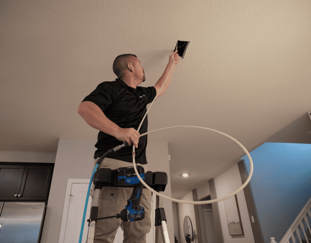 Air Titans technician applying sealant to a ceiling duct vent during sealing service in a Tampa home