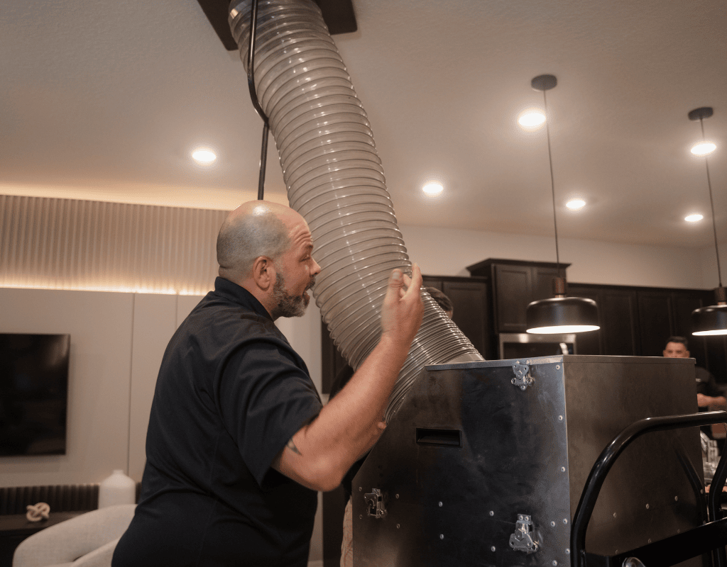 Air Titans technician adjusting duct cleaning equipment inside a Clearwater, FL residence