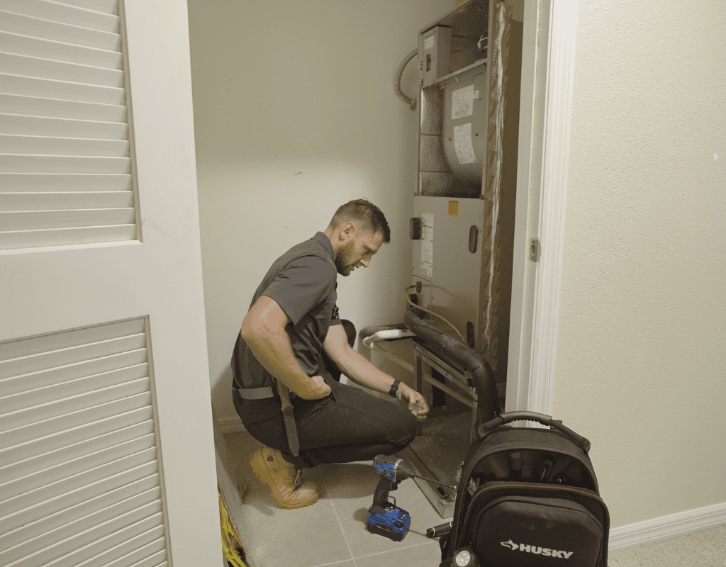 Air Titans technician inspecting and cleaning a dryer vent connection inside a Tampa home