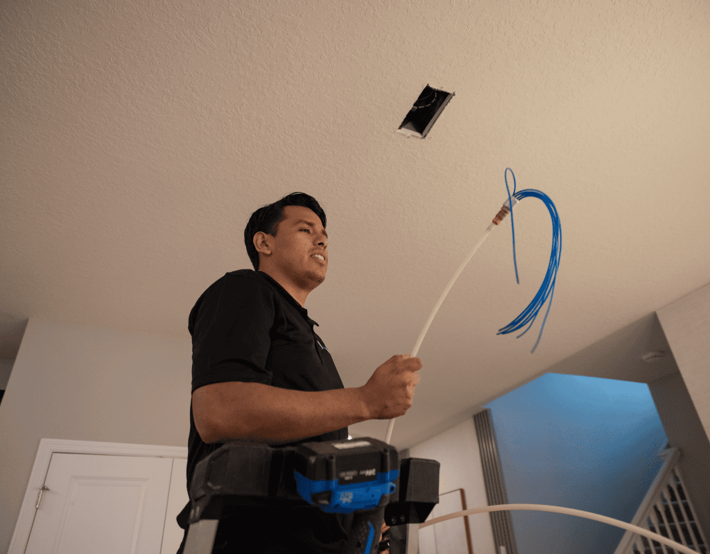 Air Titan technician examining ductwork in a Tampa ceiling for replacement