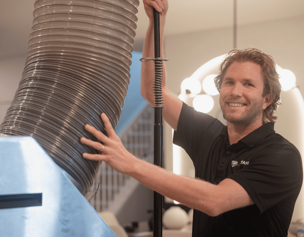 Smiling Air Titans technician inspecting ductwork during an HVAC repair in Tampa