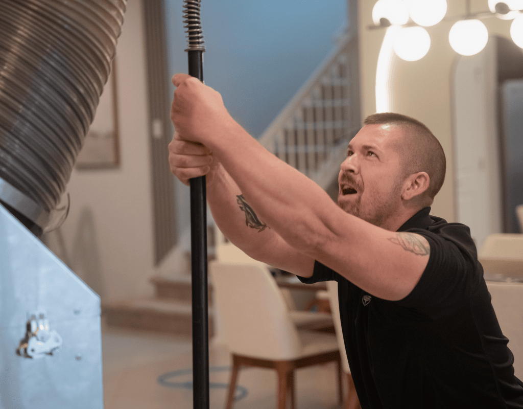 Air Titans technician positioning duct cleaning hose inside a New Tampa, FL home
